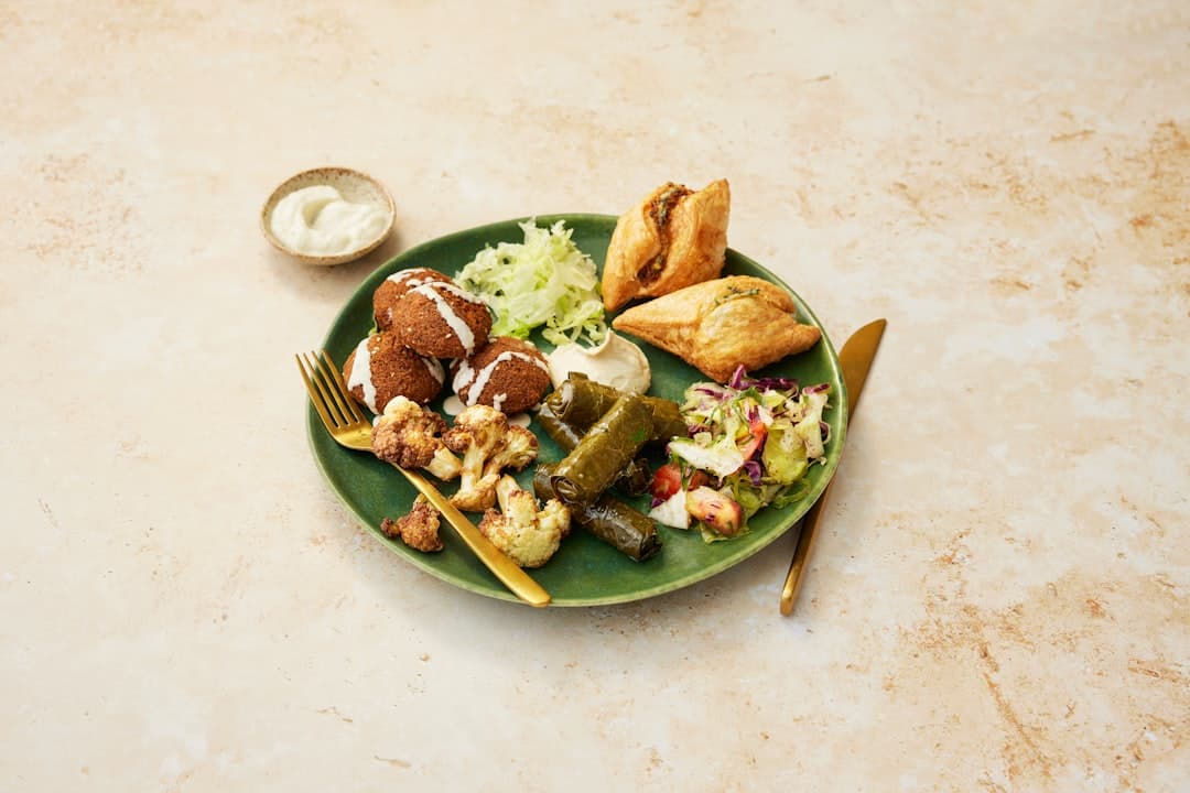 Plates of hummus, falafel and flatbread on a metal table at Hashem restaurant