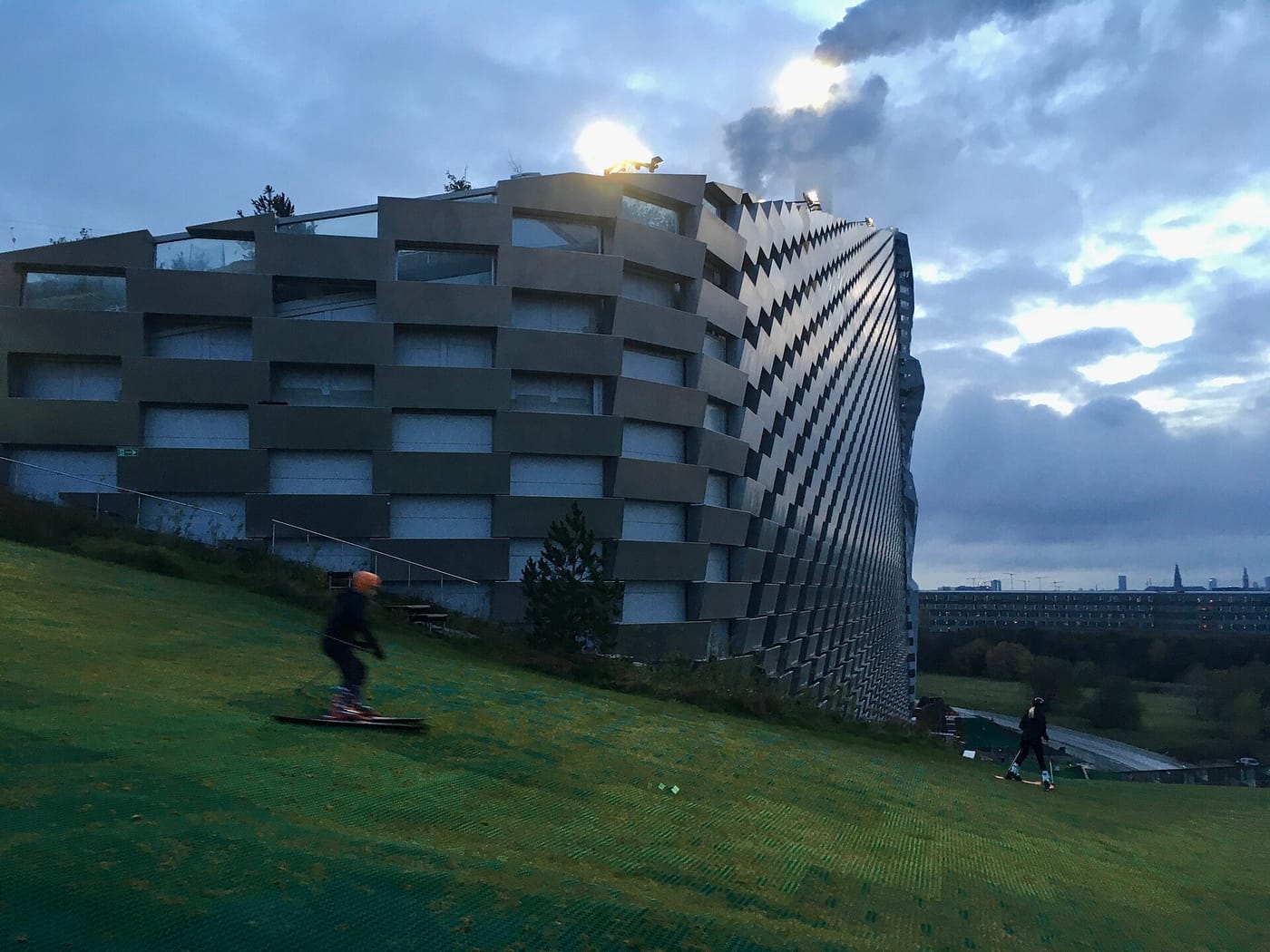 People walking on the sloping green roof of the CopenHill power plant in Copenhagen