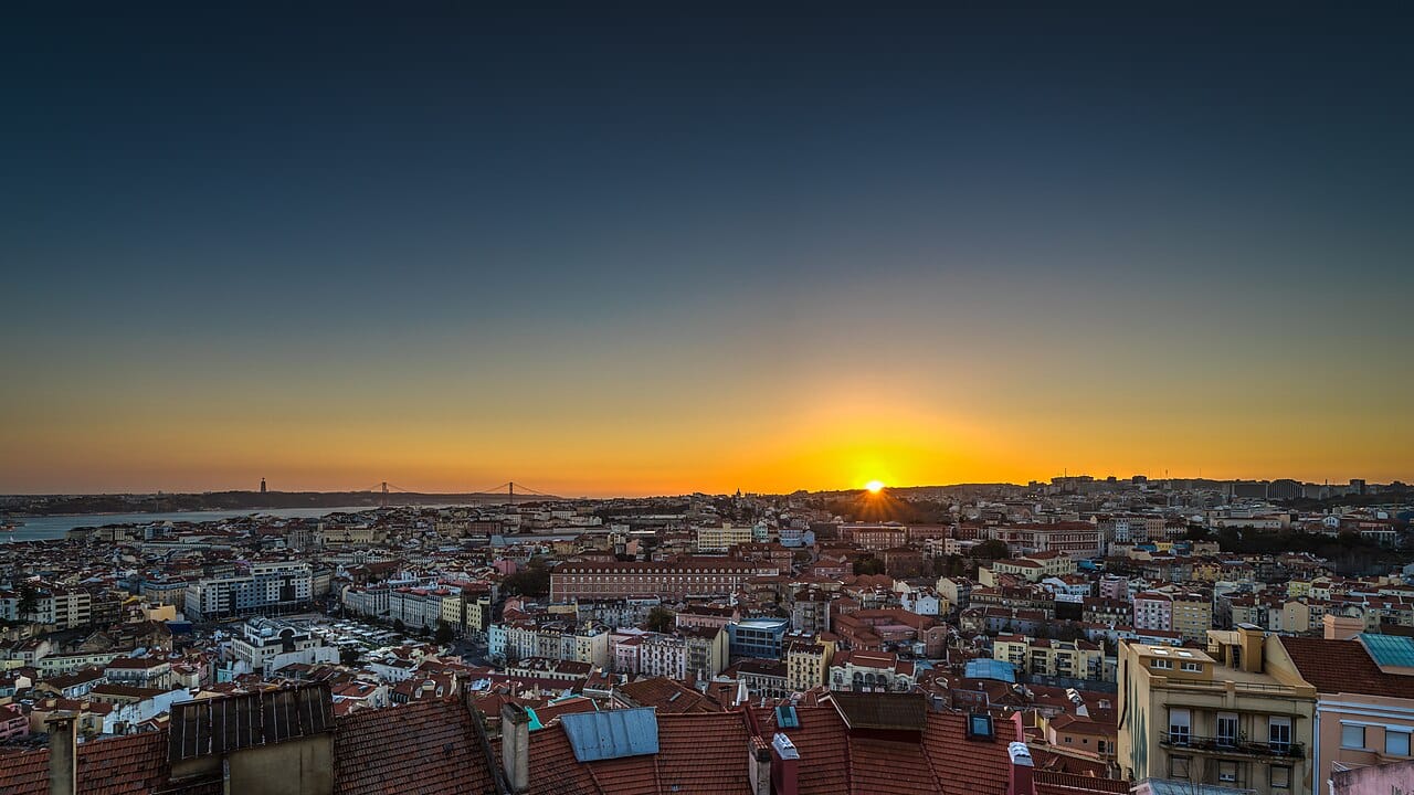 Crowd watching sunset over Lisbon's castle and river from Senhora do Monte viewpoint