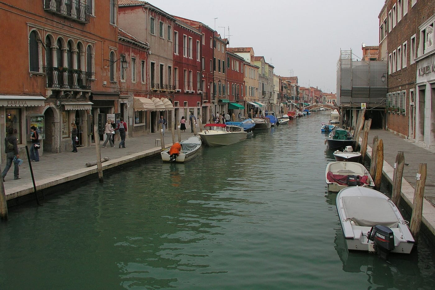 A quiet canal lined with boats on the glassmaking island of Murano, Venice